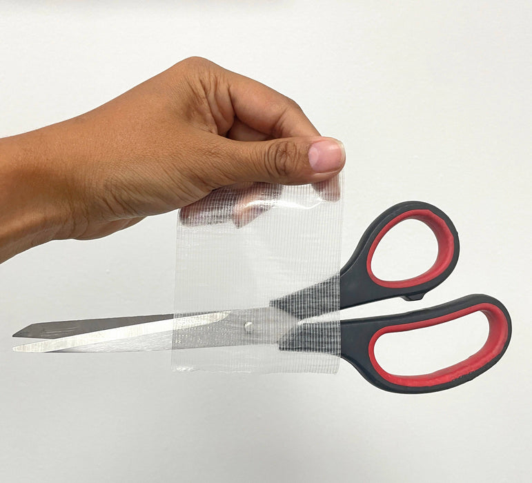 duct tape clear with scissors stuck to it to show its heavy adhesion properties