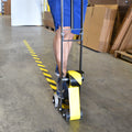 Guy using floor tape dispenser tool with his foot to easily apply tape on floor without bending over