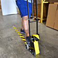 Guy pushing floor  yellow and black color safety hazard warning tape dispenser tool with his foot to easily apply tape on floor without bending over
