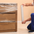 Individual wrapping up a furniture with stretch wrap packaging plastic film