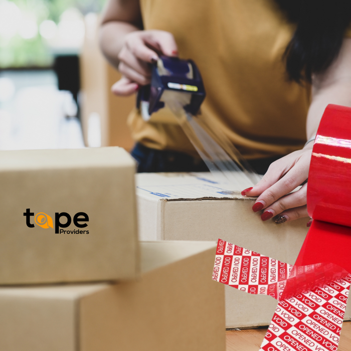 woman showing application of the "OPENED VOID" tape onto some cardoboard shipping boxes, tape providers logo on a box