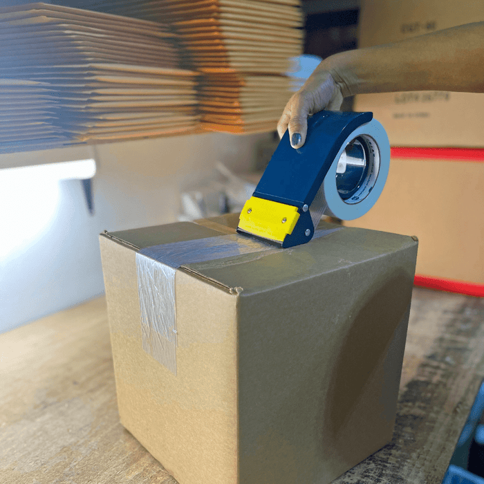 Metal Filament Tape Dispenser with a roll of tape loaded in it used to seal a shipping box