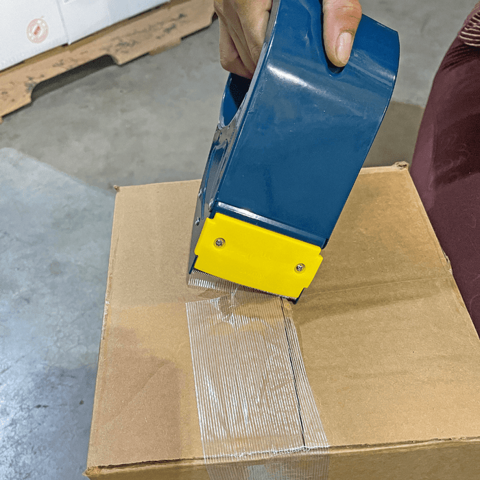 Close up of filament tape gun being used on a shipping box