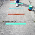 Person stepping on colored floor marking tape applied on concrete sidewalk  